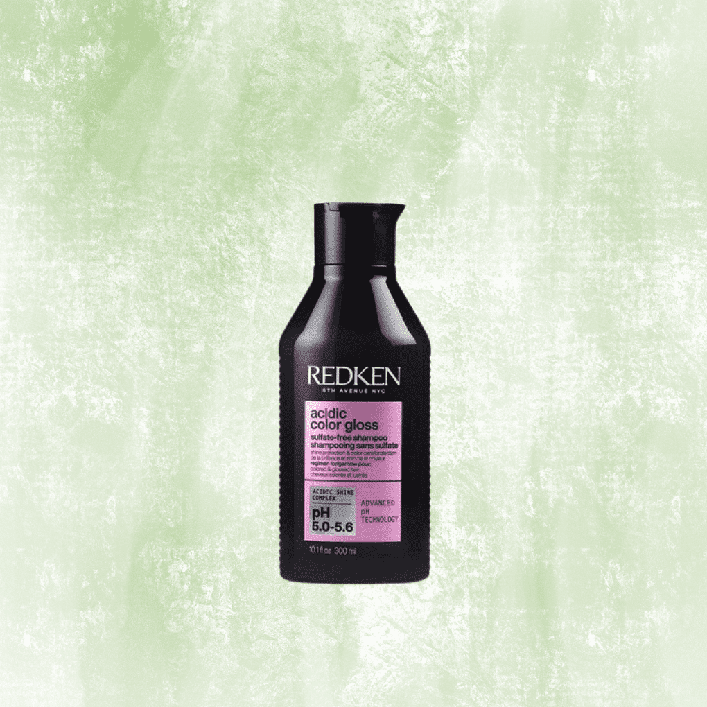 Redken Acidic Color Gloss Shampoo bottle against a textured green background.