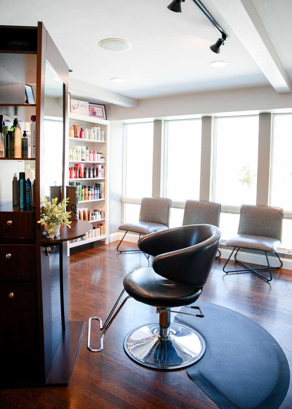 Modern salon interior with styling chair, large mirrors, and shelves of hair products.
