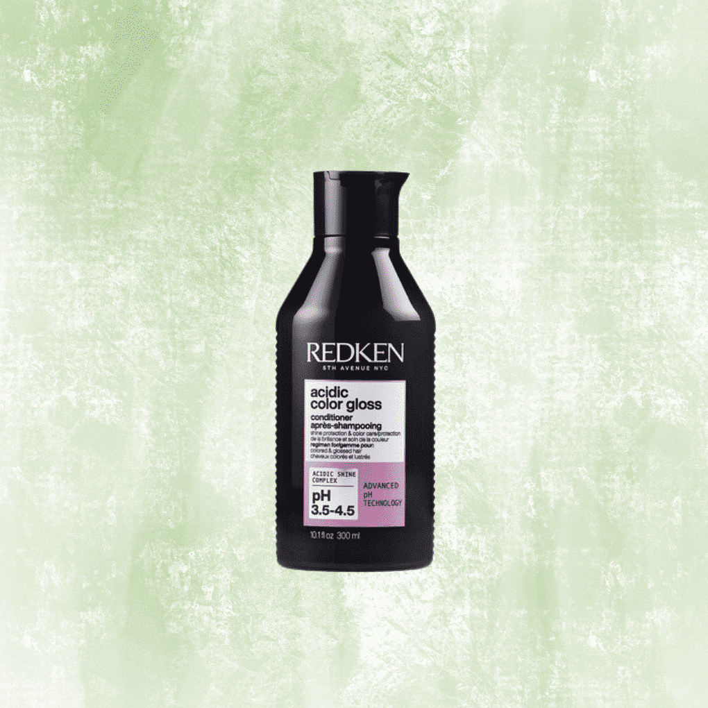 Redken Acidic Color Gloss Conditioner bottle on a textured green background.