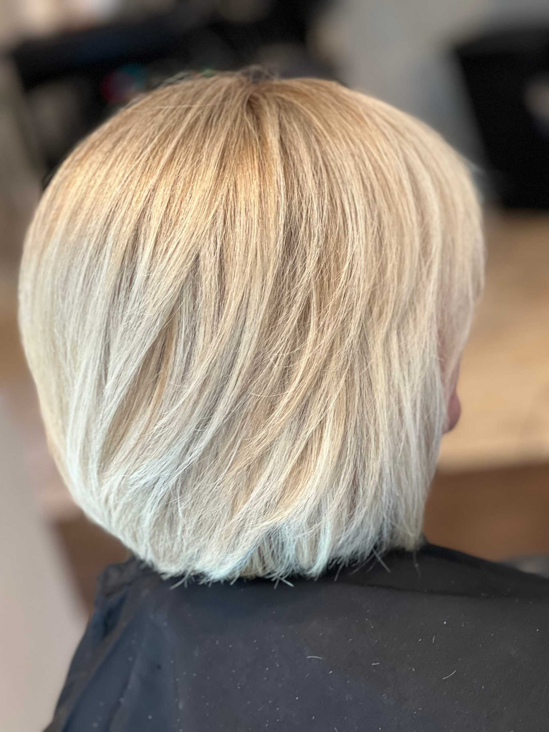 Short blonde bob haircut viewed from the back at a salon.